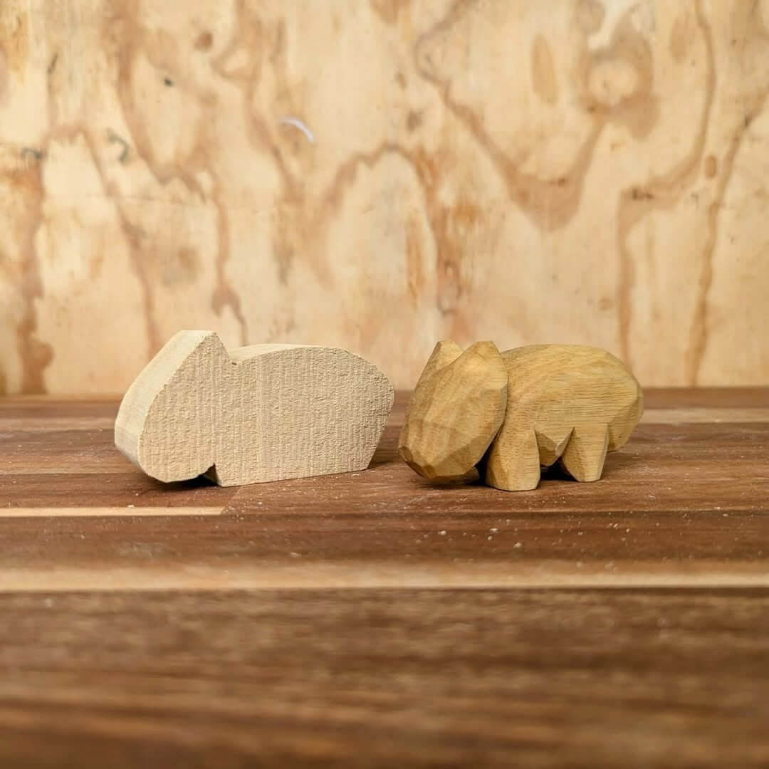 Two wooden carvings of a wombats next to each other